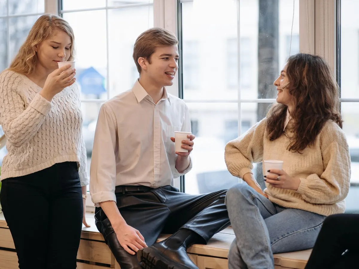 Tres amigos conversando con un café junto a una ventana