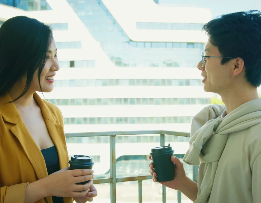 Dos amigos conversando con un café en un balcón
