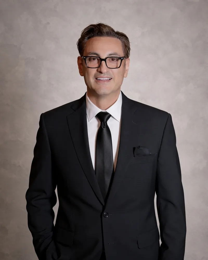 Pedro Lira, de traje y con gafas, en un retrato de estudio