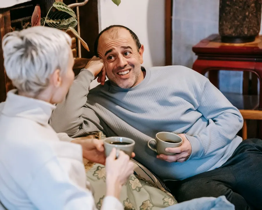 Una pareja conversando con una taza en el sofá de su casa